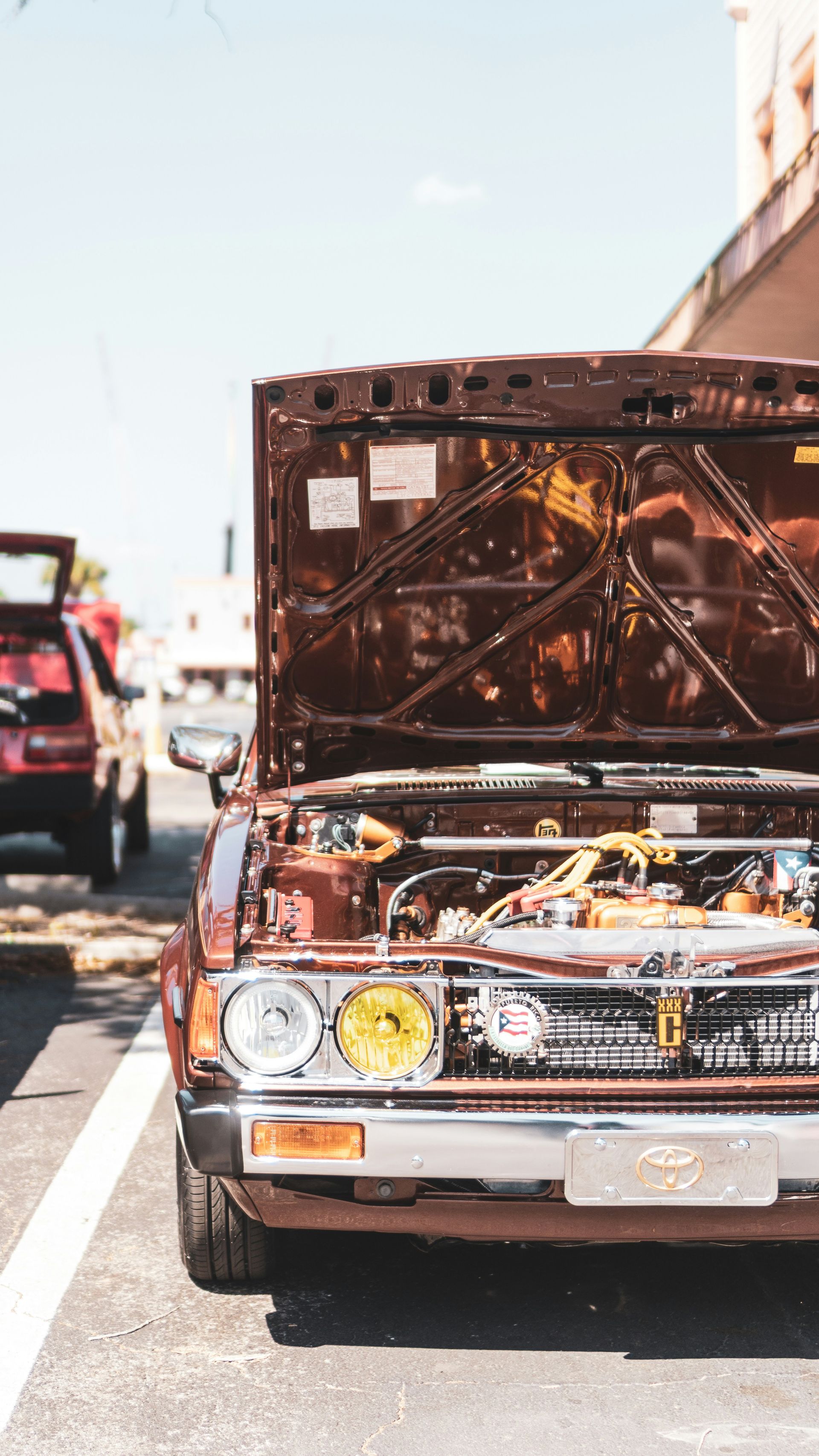A classic brown car with its hood open